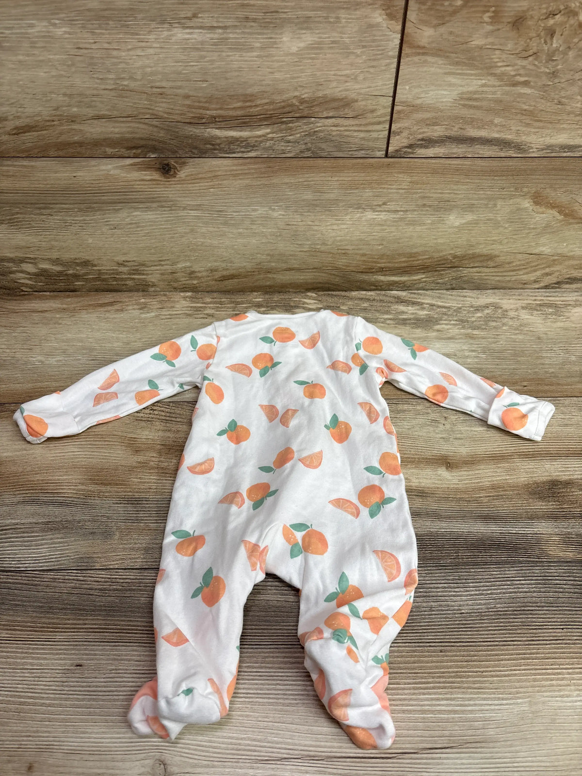Front view of Just One You white sleeper, size 3M, with orange fruit print and footed legs on a wood floor