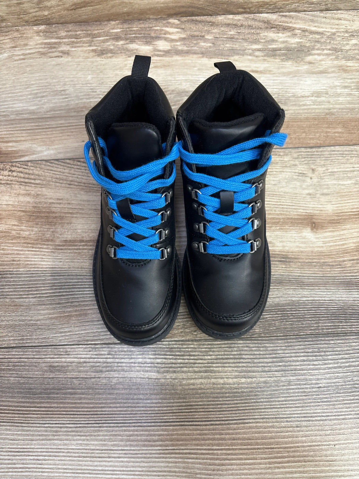 Black kids boots with bright blue laces on wood floor, children's footwear resale