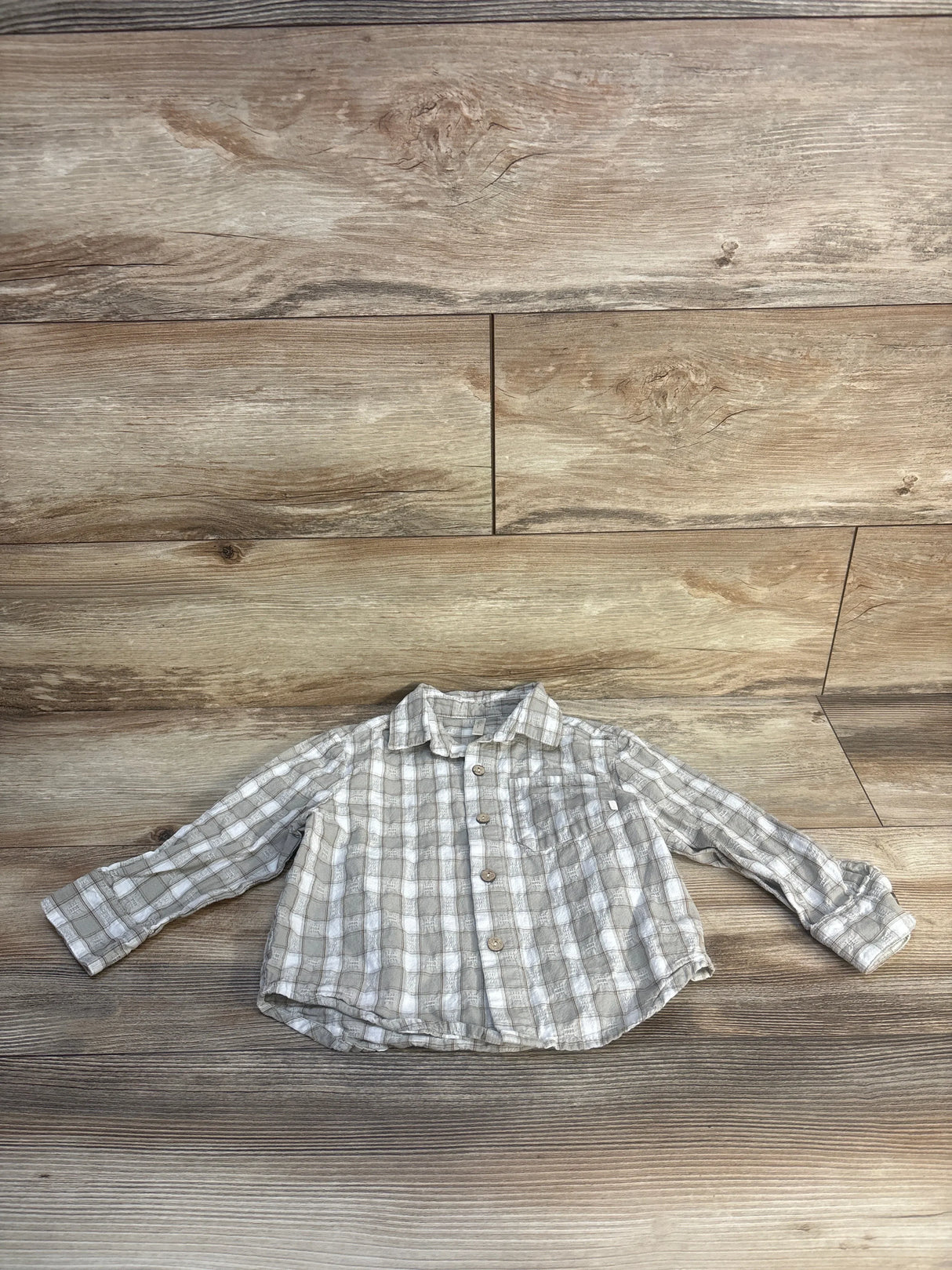 Light gray plaid long sleeve button-up toddler shirt on wood background