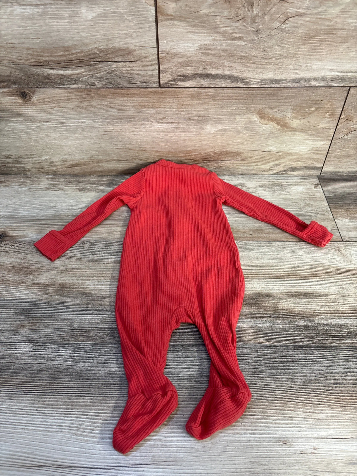 Flat lay of red Old Navy ribbed sleeper showcasing long sleeves and attached feet on wood grain background