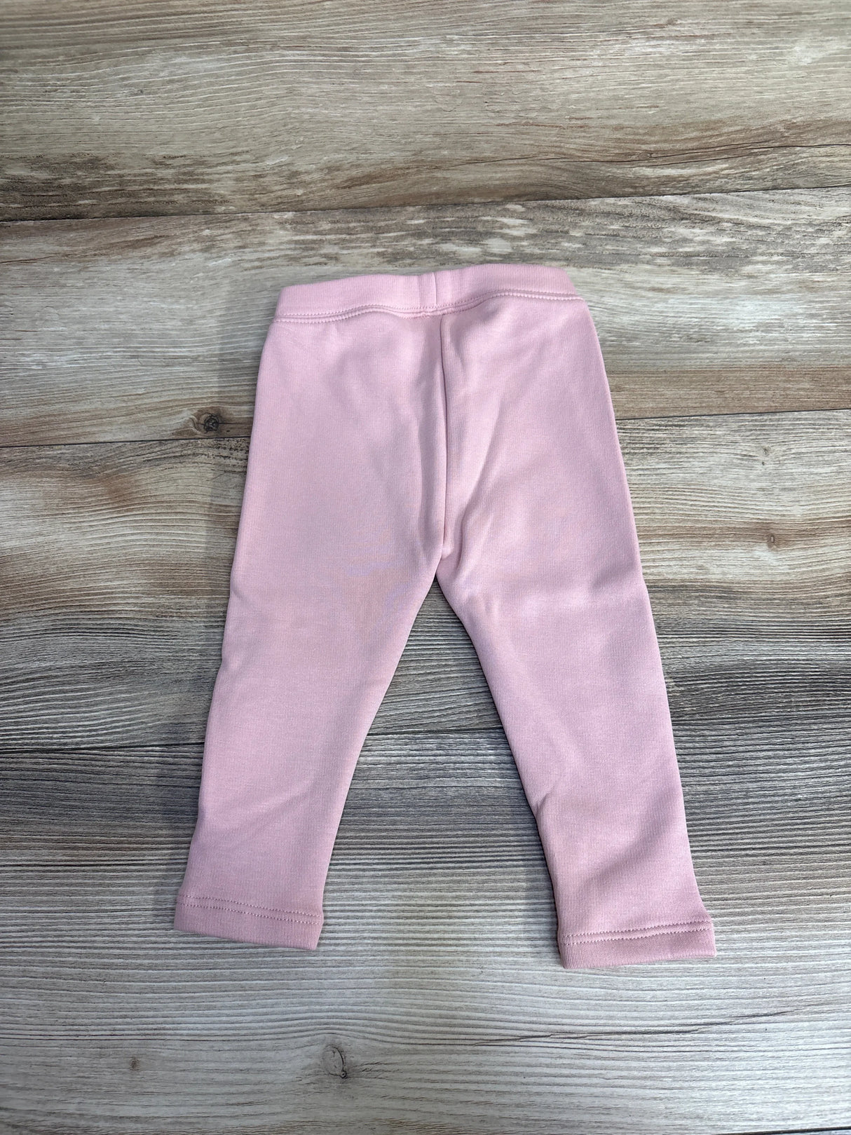Light pink baby leggings on wood background, kids clothing resale item