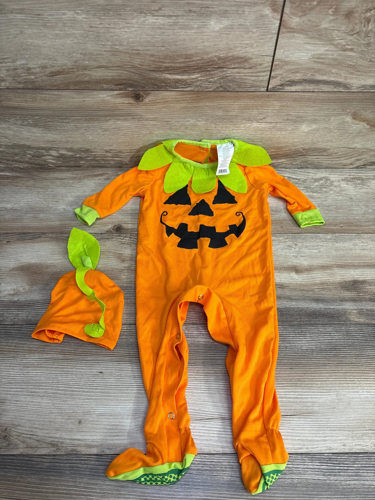 Orange pumpkin-themed baby onesie with green accents and matching hat for Halloween