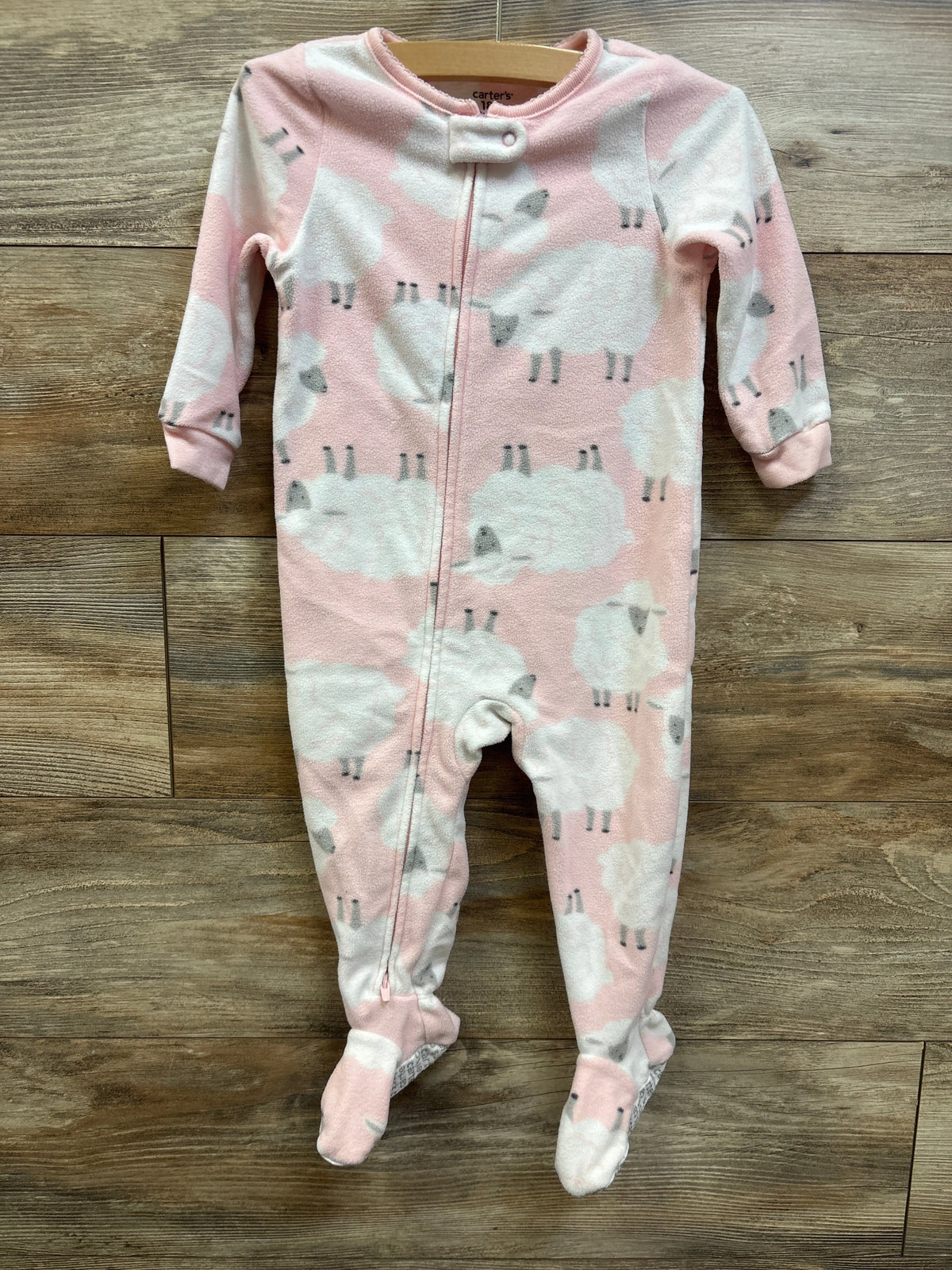 Front view of Carter’s pink blanket sleeper showcasing sheep pattern, long sleeves, front zipper, and built-in feet on a wood floor