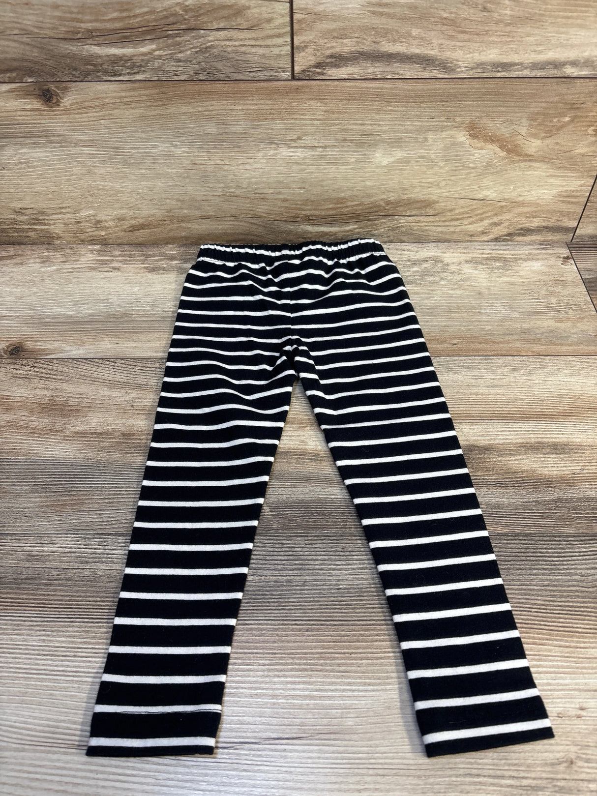 Black and white striped kids leggings on wood floor, children's resale clothing.