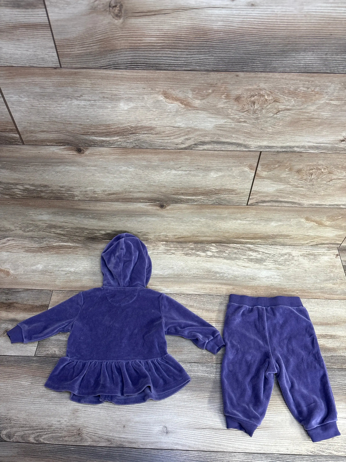 Purple velour baby hoodie with ruffled hem and matching pants on wood floor