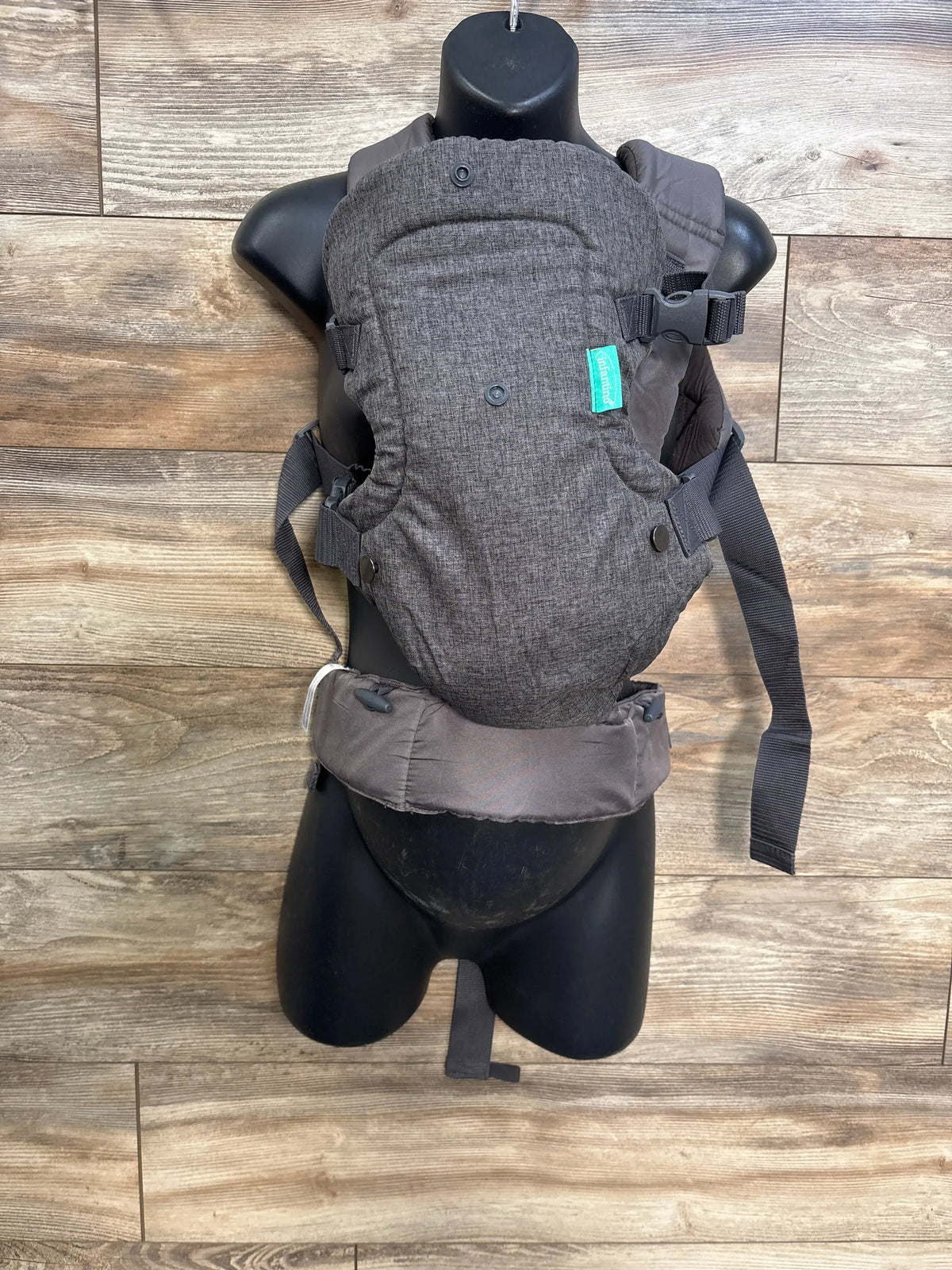 Front view of gray Infantino Flip 4-in-1 convertible baby carrier showing padded waist belt and adjustable straps on a black mannequin