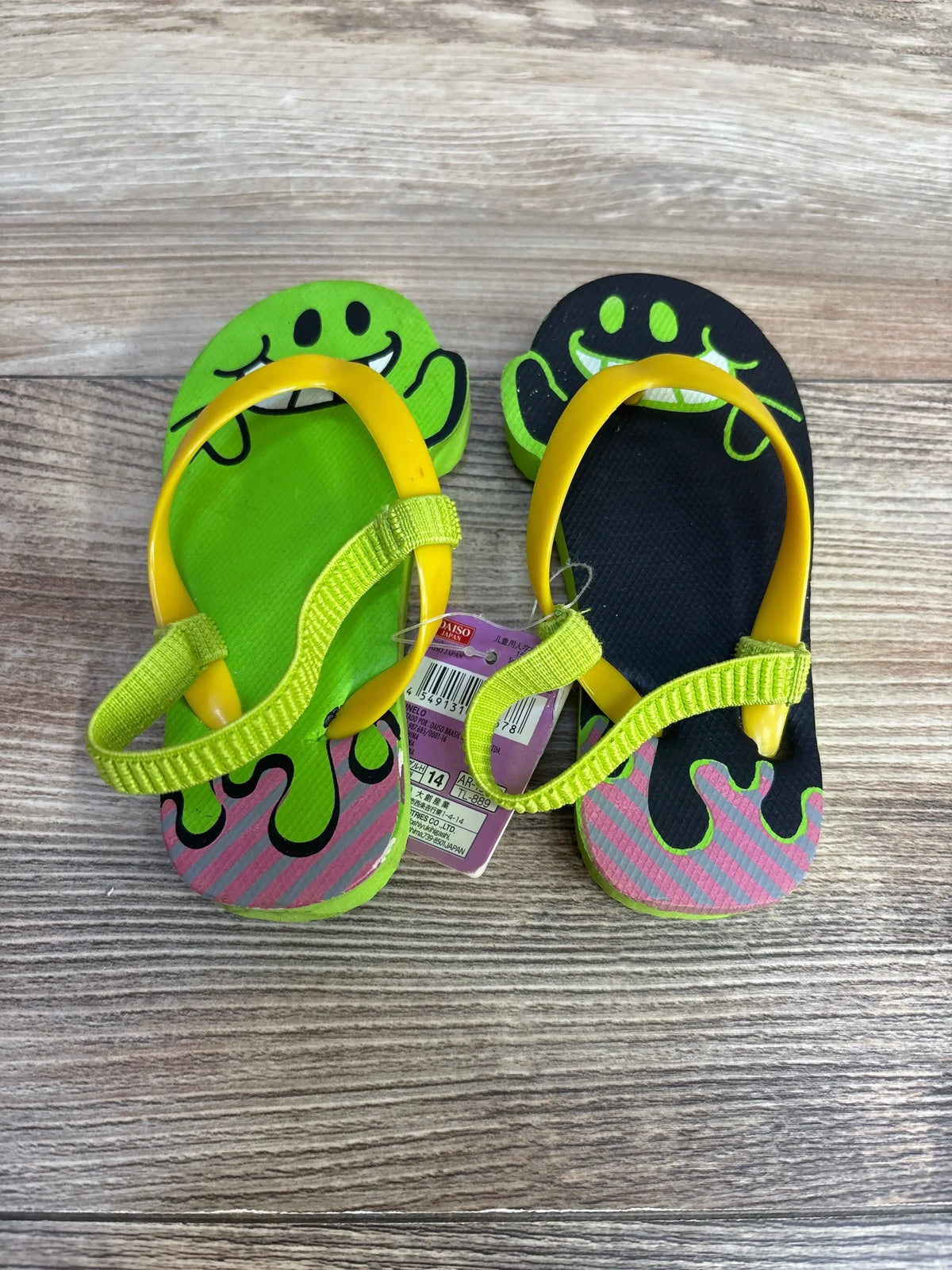 Top view of kids’ lime and black flip flops size 6-7 with yellow straps, heel support and smiling-face design