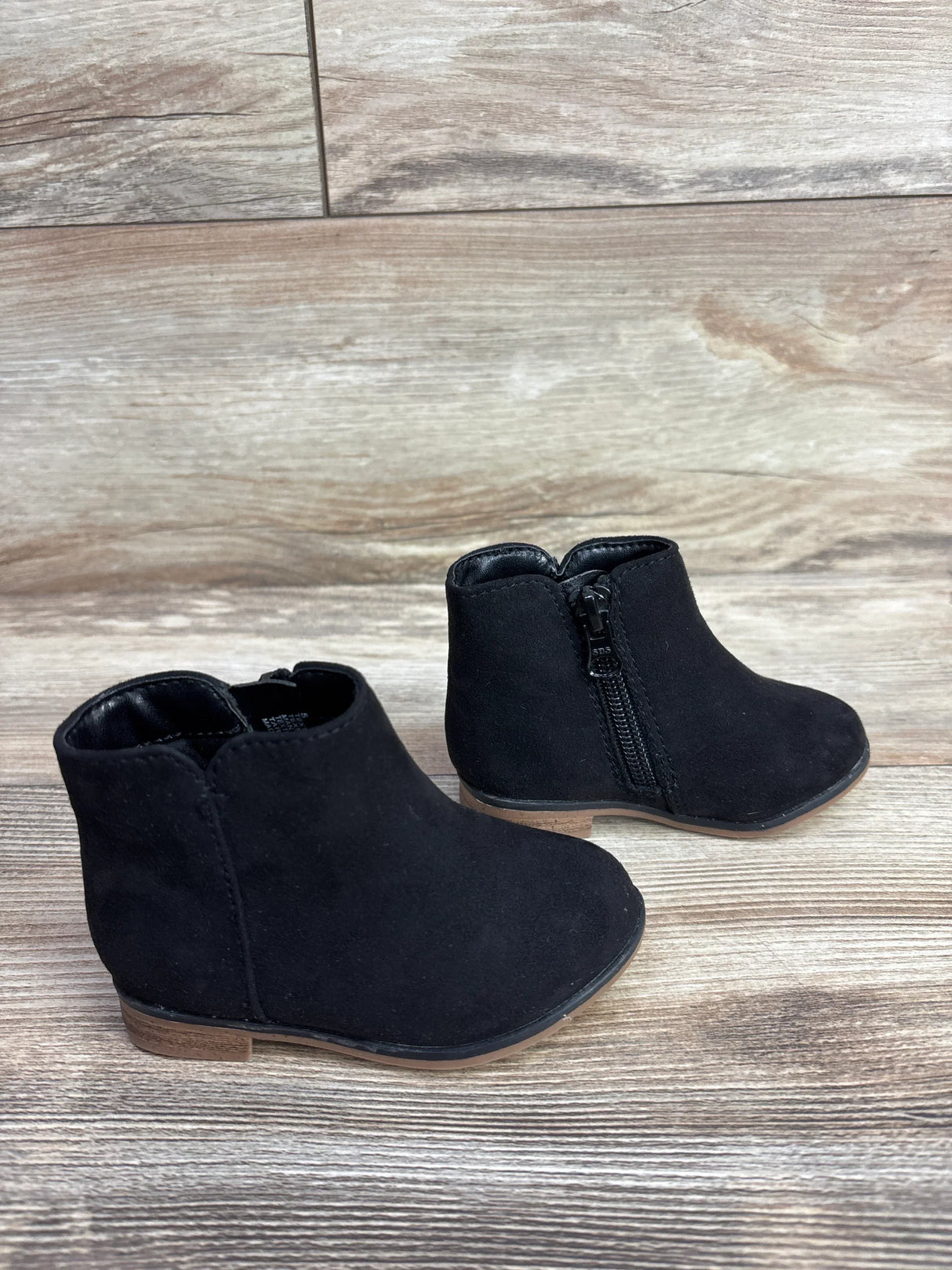Black toddler ankle boots with side zippers on a wooden floor, kids footwear
