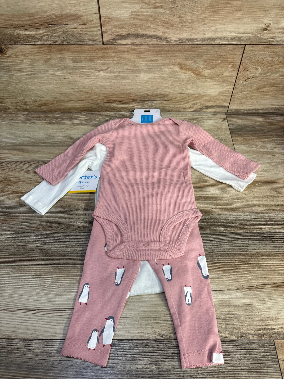 Front view of Carter’s 3-piece bodysuit set showcasing pink waffle knit and white bodysuits on a wood background
