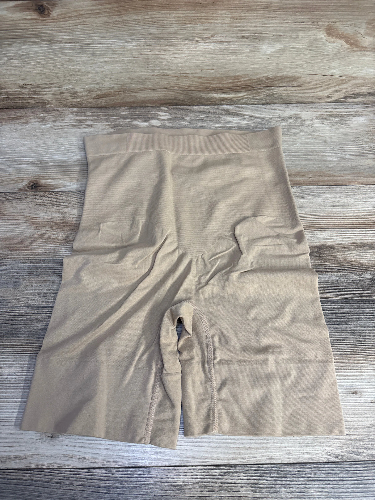 Beige high-waisted shapewear shorts on wood surface, seamless compression garment