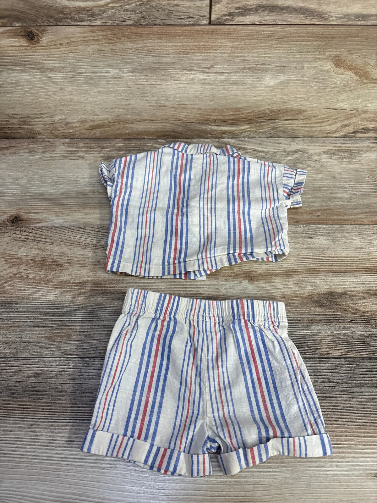 Flat lay of cream striped button-up baby shirt and matching shorts, newborn 0-3 months, on white background