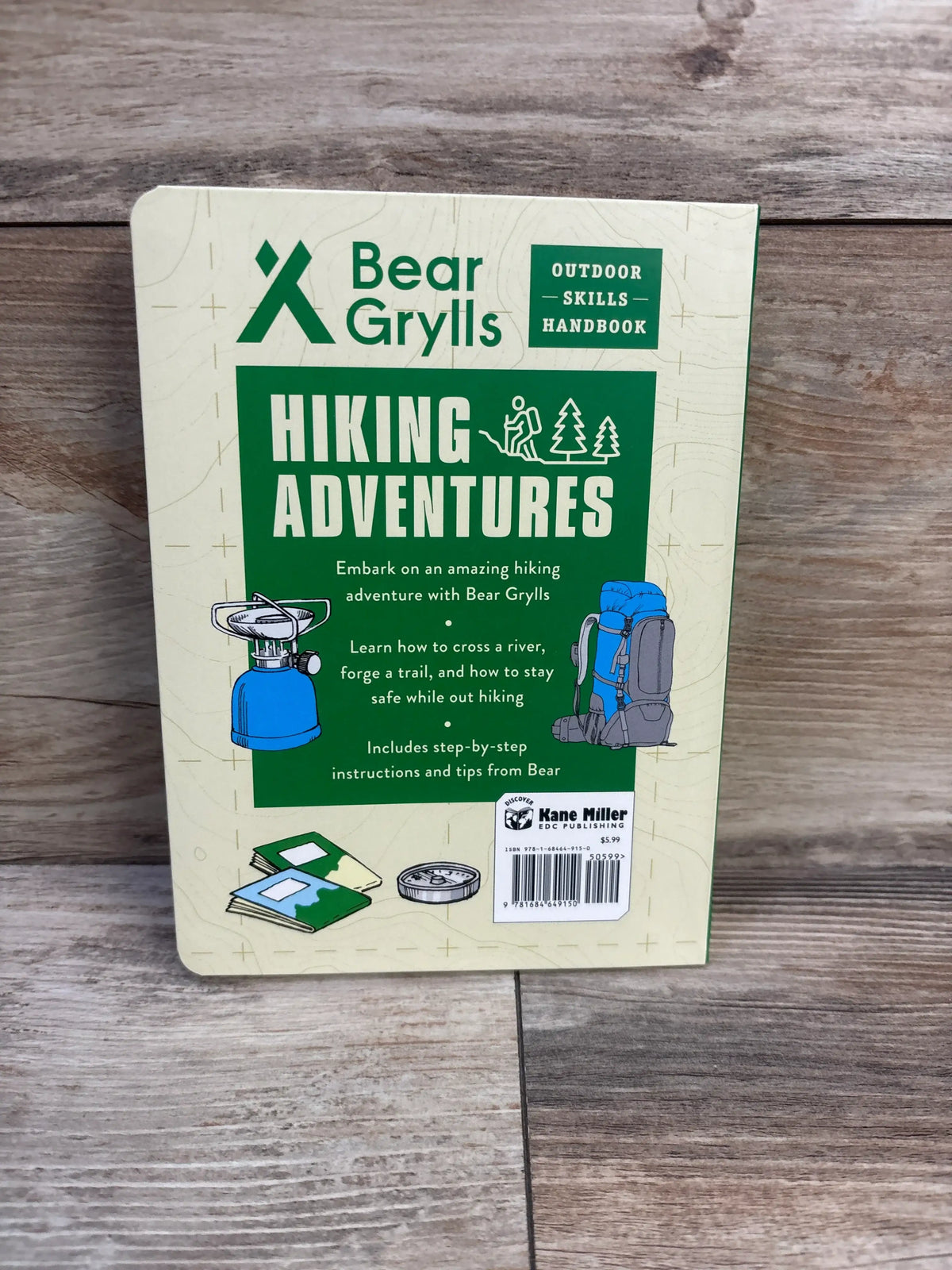 Back cover of Hiking Adventures Bear Grylls Outdoor Skills Handbook showcasing hiking skills guidance on a wooden surface