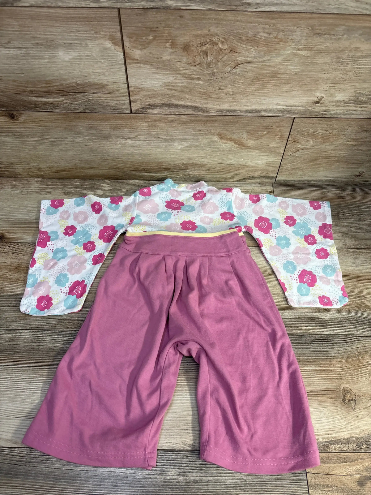 Pink and floral baby kimono romper on wooden floor