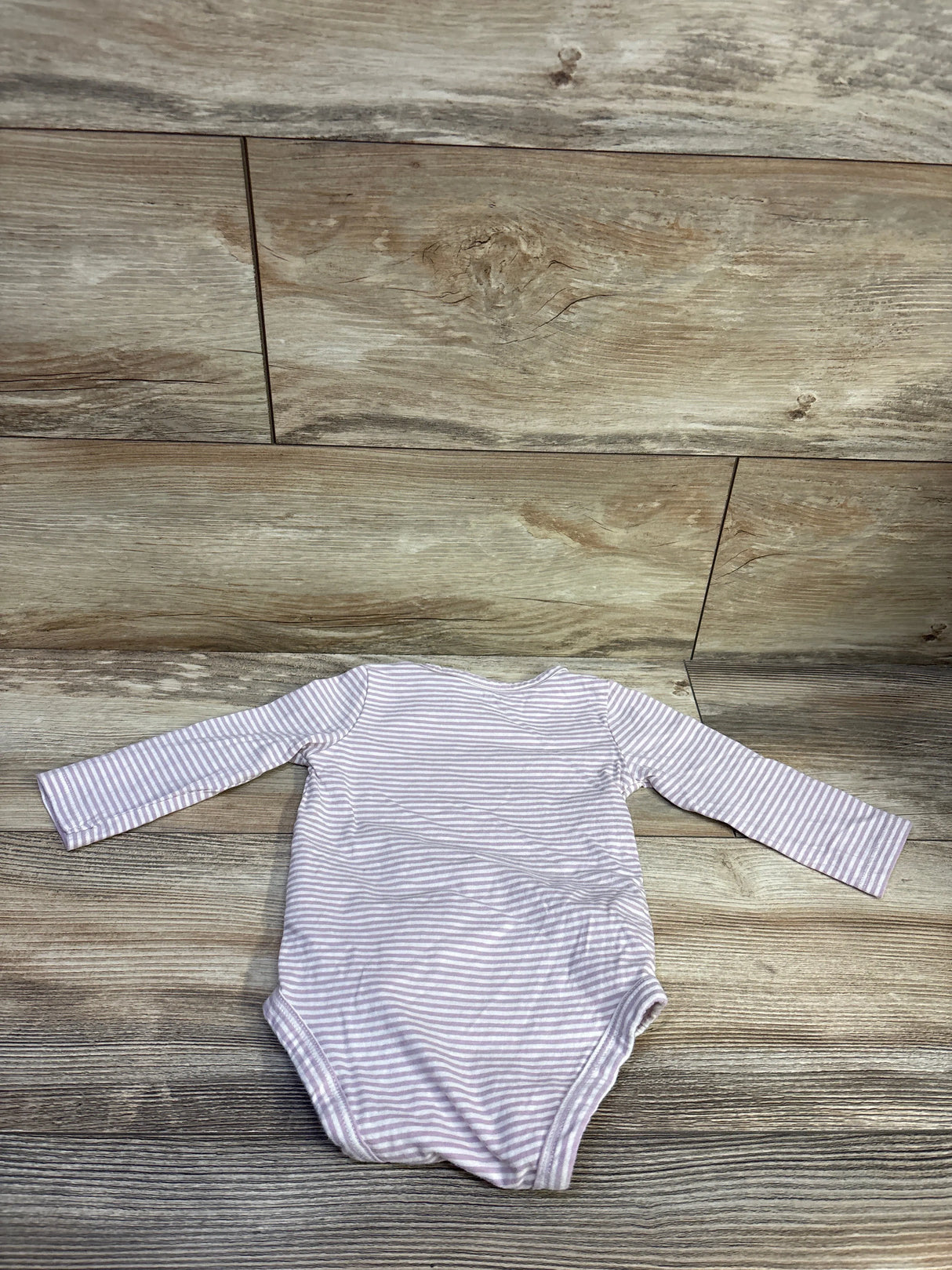Back view of Carter’s Auntie’s Little Bean bodysuit showcasing purple and white stripes and long sleeves on a wood floor