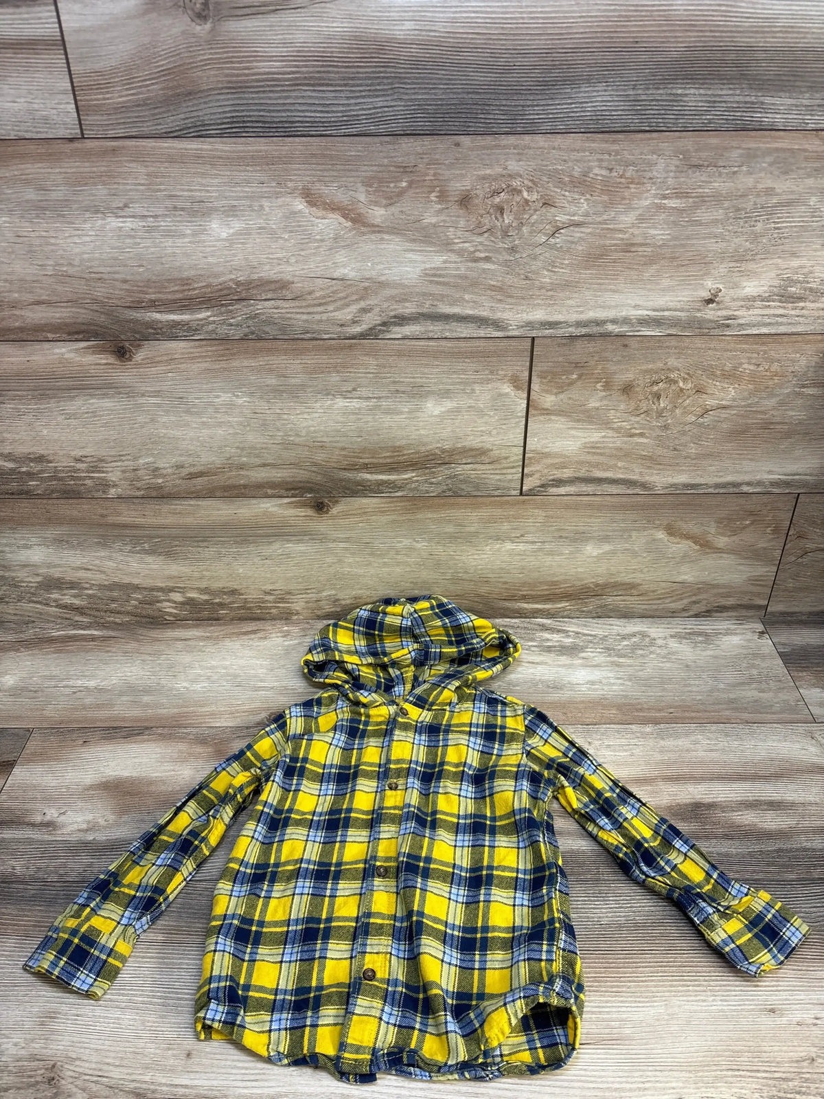 Yellow and blue plaid hooded button-up flannel shirt for kids on wood background