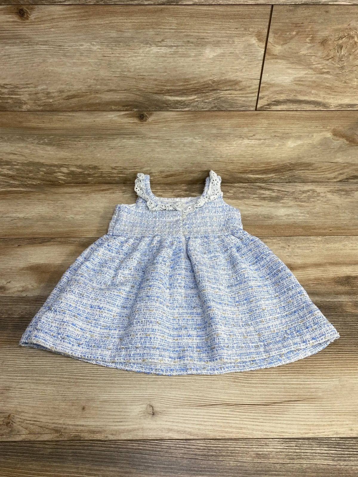 Flat lay of Janie and Jack blue tweed dress (2T) showing eyelet ruffle straps, smocked bodice, and full skirt on wood floor