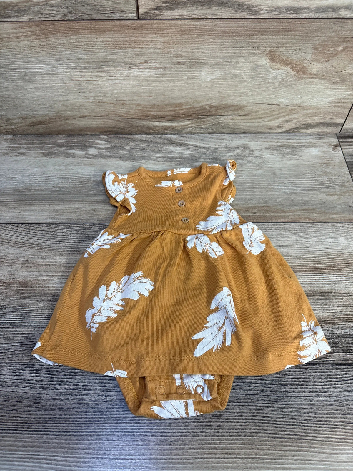 Front view of Carter’s soft yellow Henley bodysuit dress with buttoned neckline and white leaf pattern