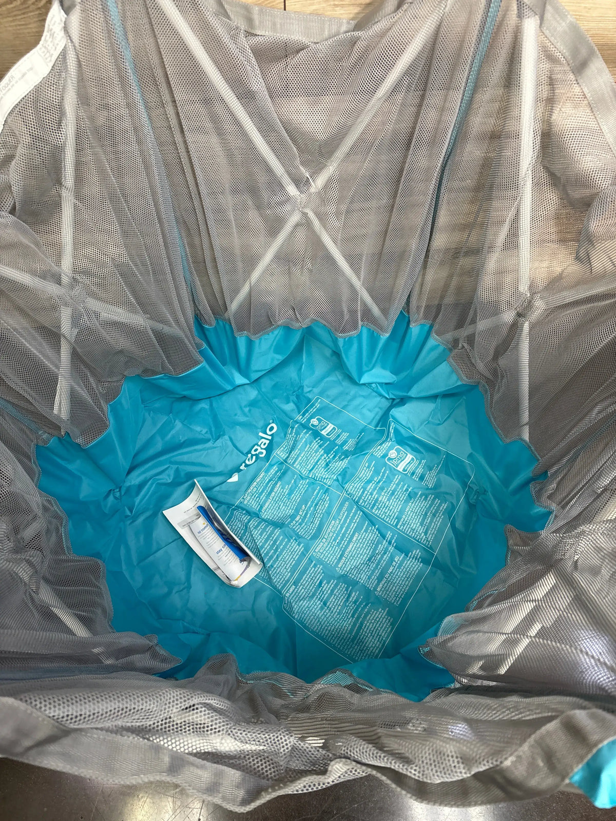Top-down view of Regalo My Play portable 6-panel play yard showing teal nylon bottom and gray mesh walls