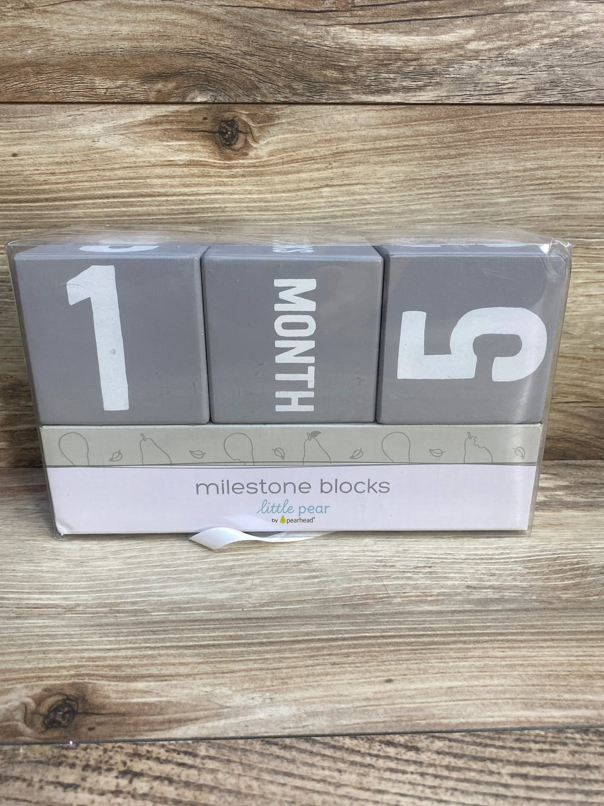 Gray milestone blocks set for baby age tracking, displaying 1 month, on wood background