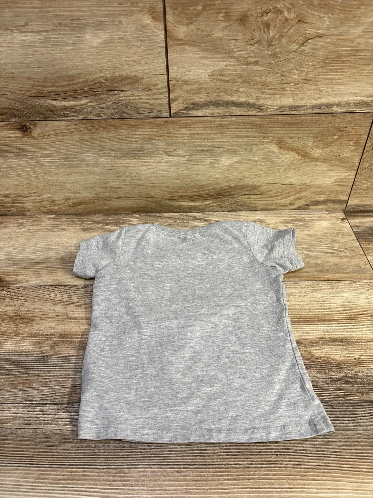 Back view of Disney Stitch graphic shirt in grey with short sleeves on a wood-look floor