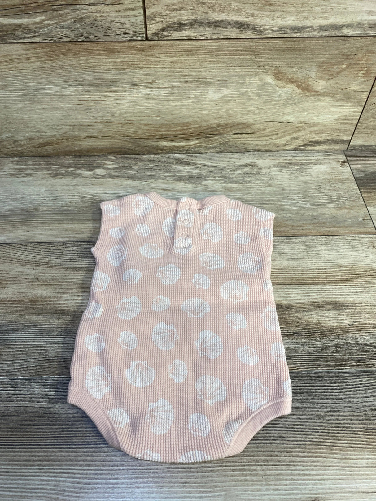 Flat lay back view of Easy Peasy tank bodysuit in peach powder with white polka dots and back buttons on wood floor