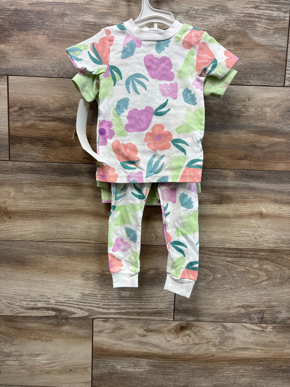 Back view of Just One You 4-piece baby pajama set showing pastel floral print top and matching leggings on wood background
