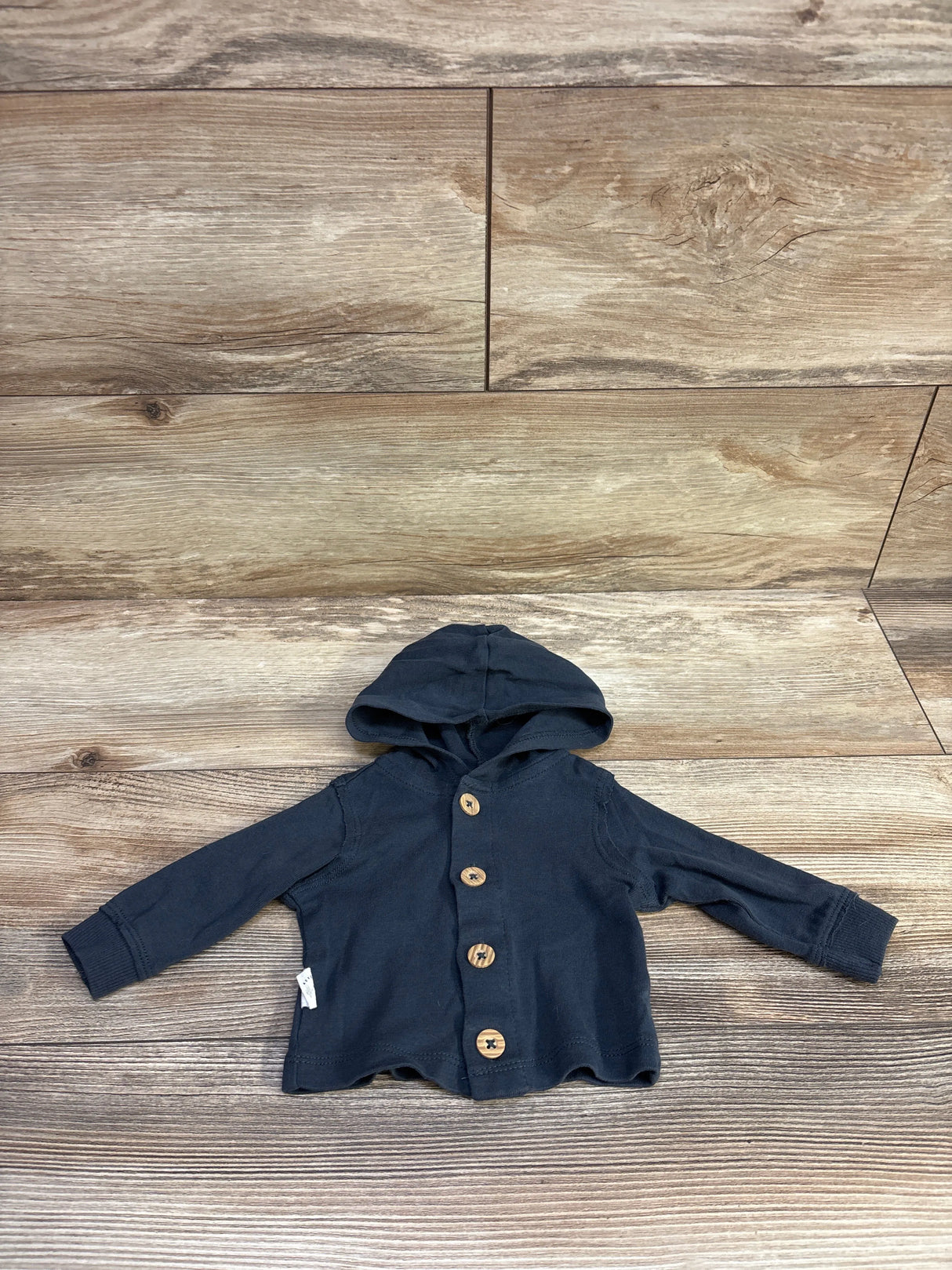Flat lay of Carter’s newborn hooded button-front shirt showcasing wooden buttons and long sleeves on wood background