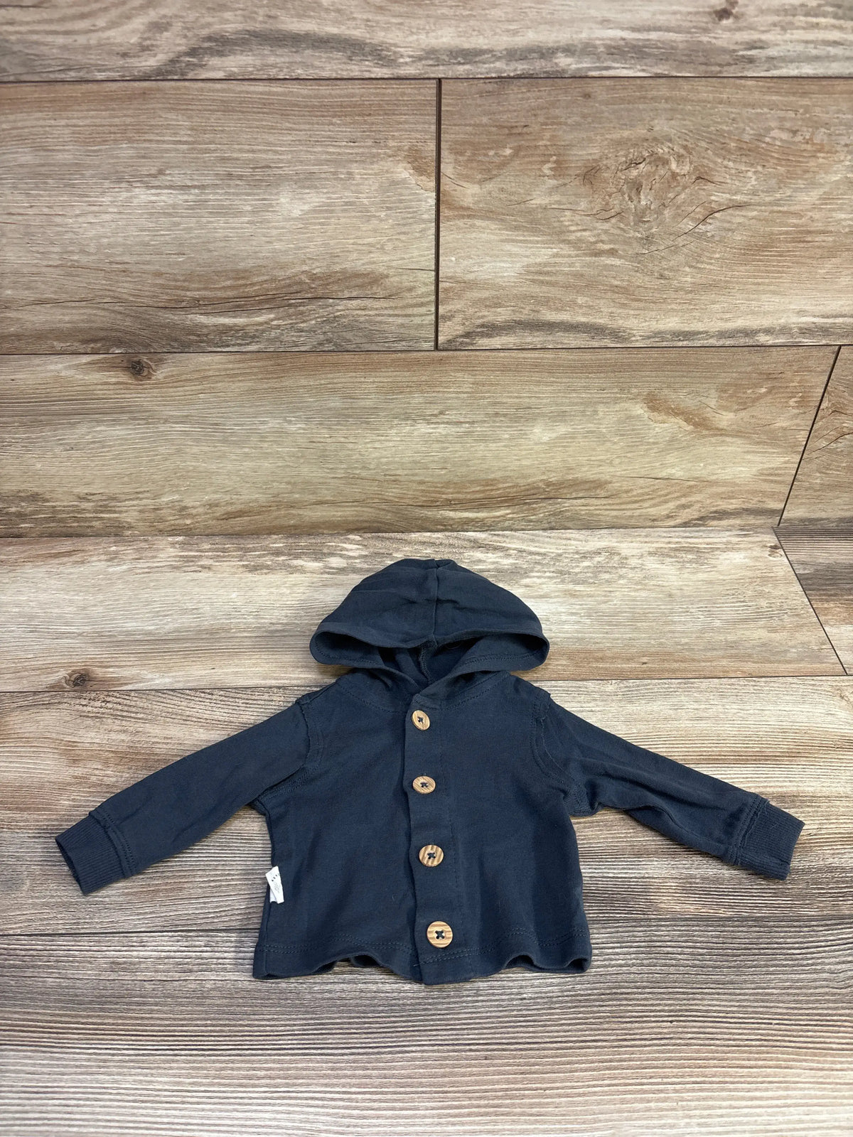 Flat lay of Carter’s newborn hooded button-front shirt showcasing wooden buttons and long sleeves on wood background