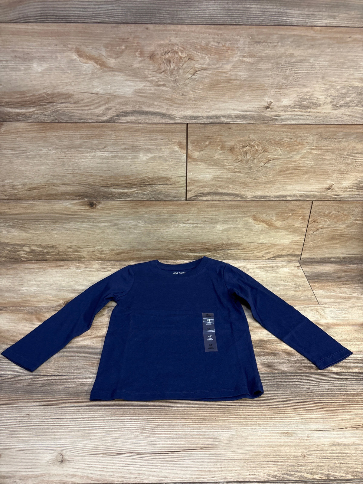 Flat lay of navy Epic Threads long-sleeve toddler shirt size 4T showcasing crew neck and front size tag on wood plank background