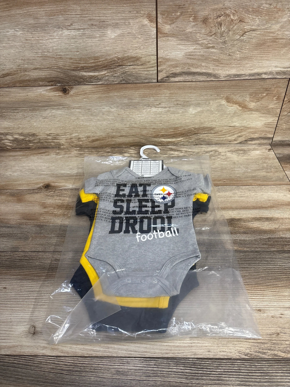 Gray Pittsburgh Steelers baby onesie in packaging on wood background, Eat Sleep Drool football