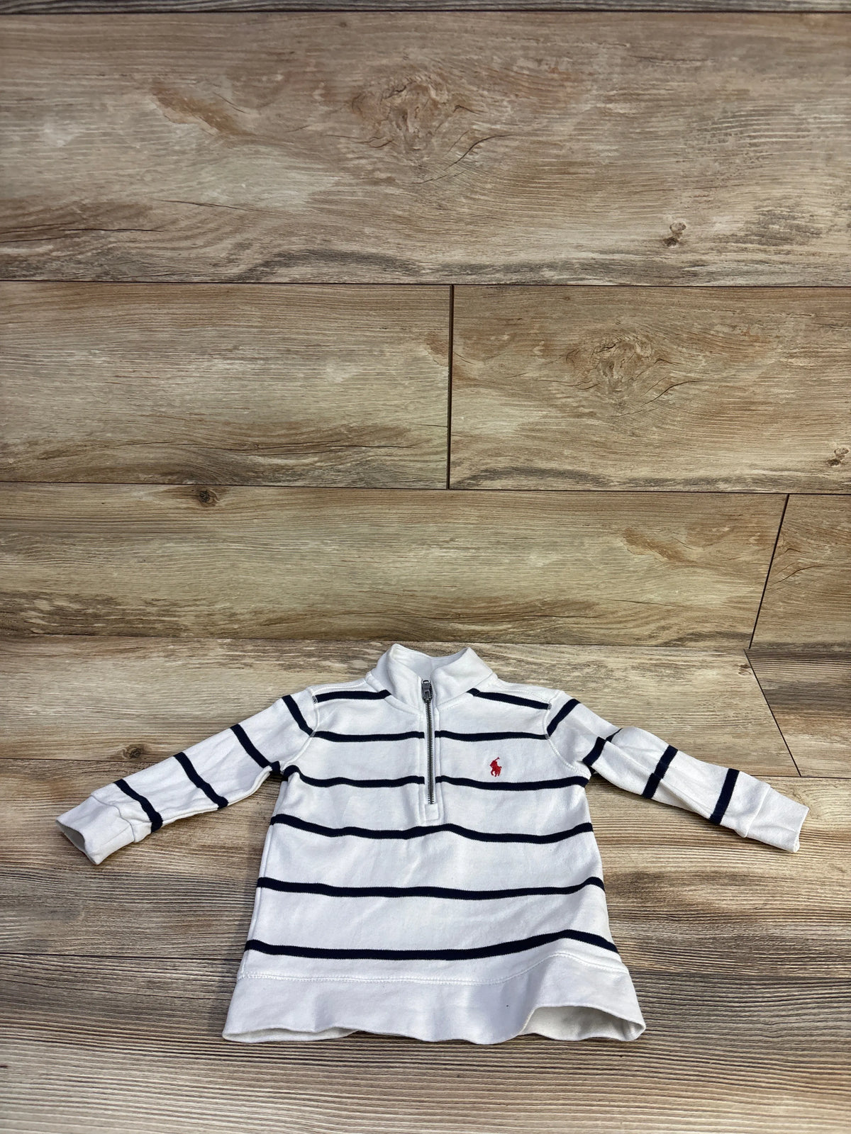 Flat lay of Ralph Lauren half-zip sweater 24M with navy stripes and red pony logo on wood background