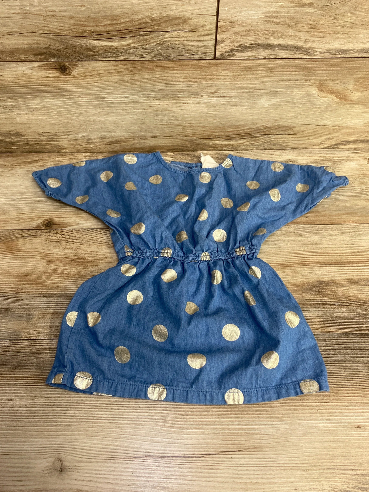Blue toddler dress with gold polka dots, elastic waist, and short sleeves on wooden floor
