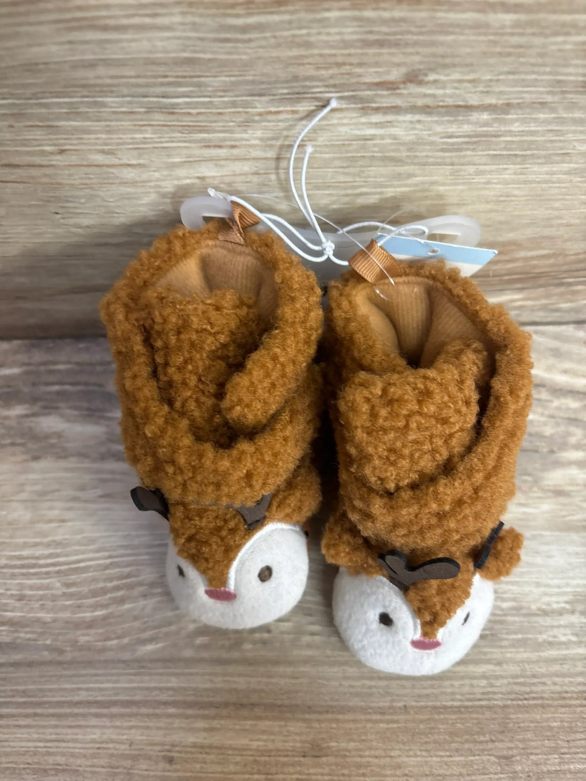 Soft brown reindeer baby booties with white faces, perfect for newborns and infants.