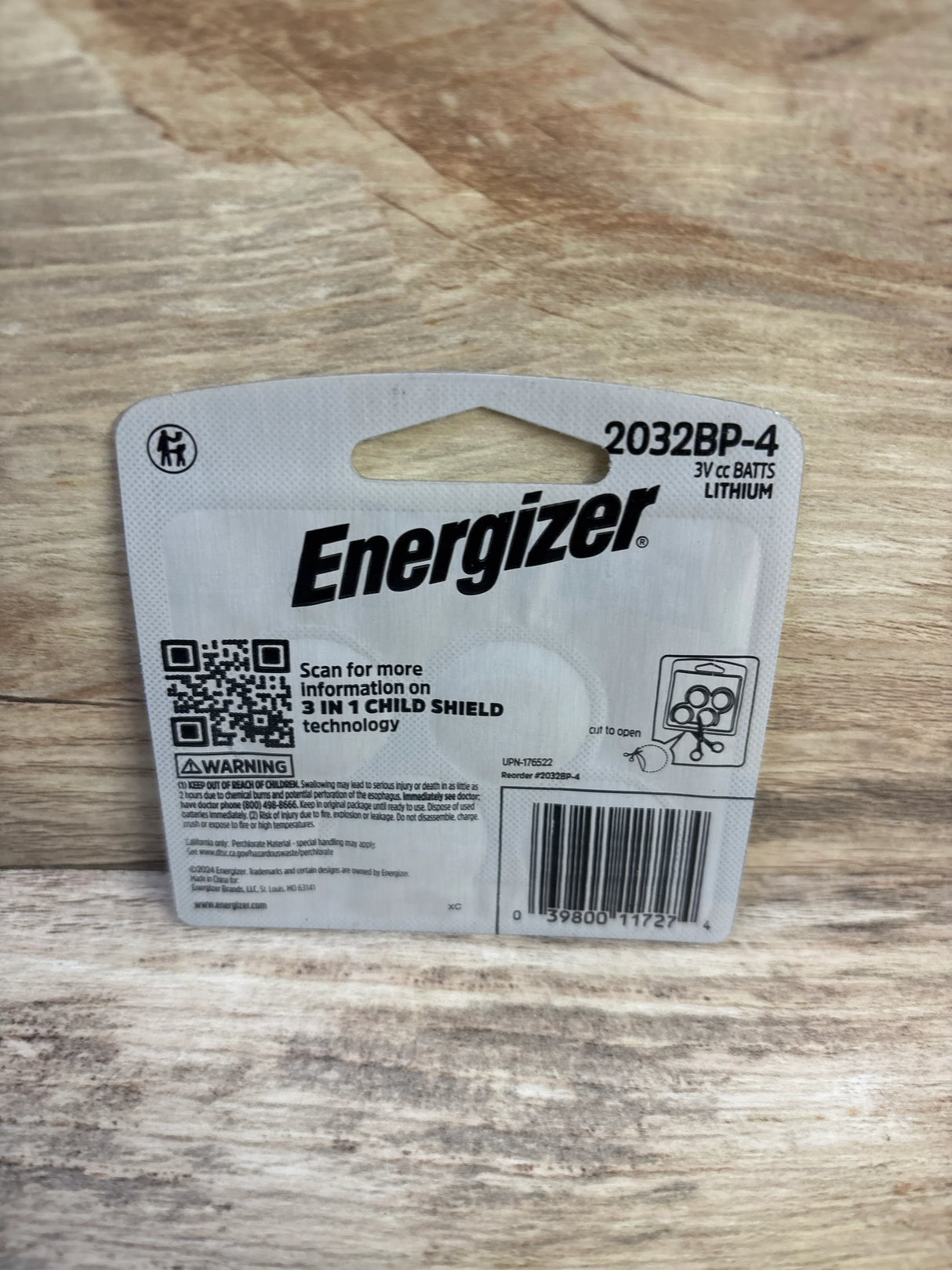Back view of Energizer 2032 coin cell battery 4-pack showcasing Energizer logo, model 2032BP-4 and child-shield packaging on wood background