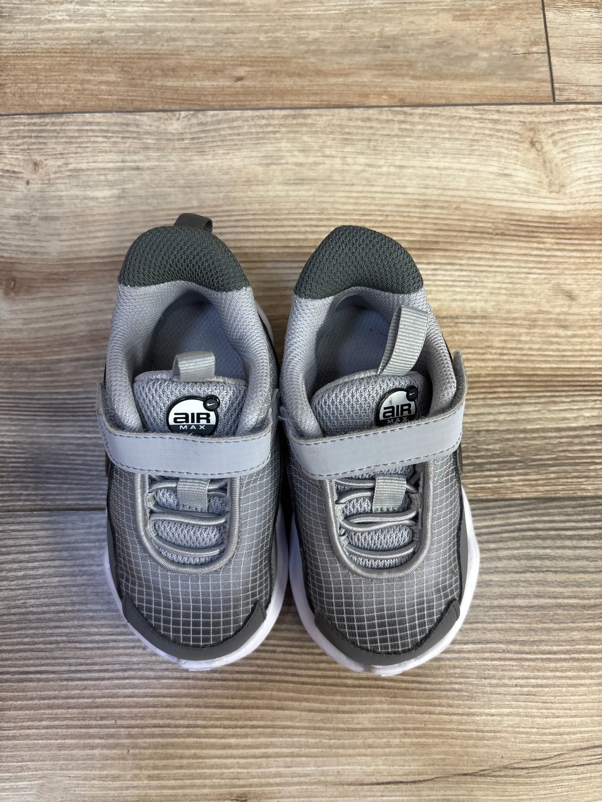 Top view of Nike Air Max Nova TD toddler sneakers in Wolf Grey, size 6C, showcasing hook and loop closures on a wood floor