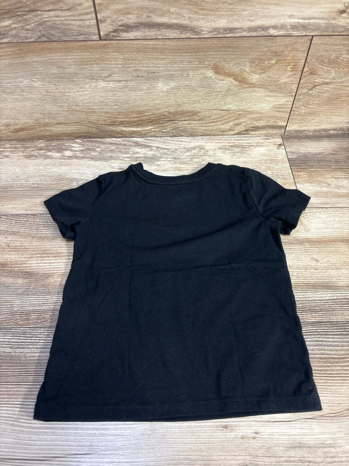 Back view of Cat and Jack black short-sleeve toddler t-shirt showing crew neckline and plain fabric on wood floor