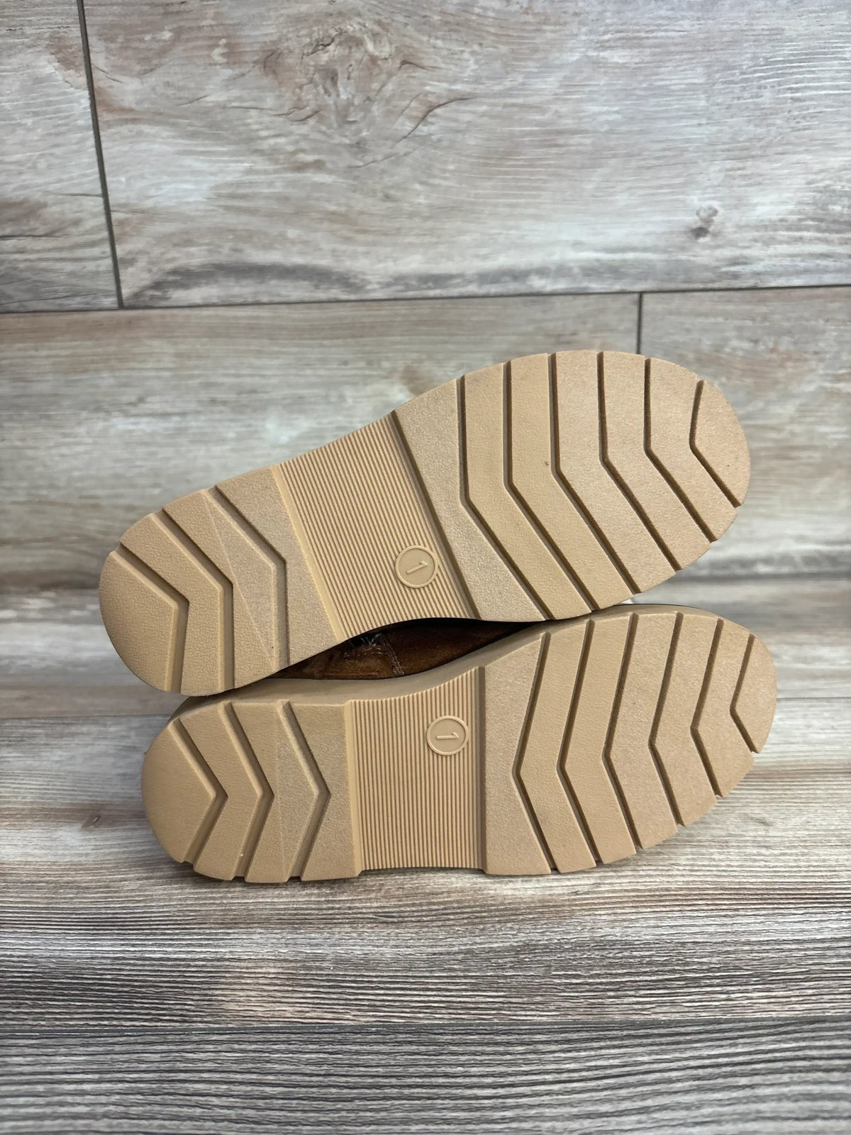 Pair of kids' shoes with non-slip rubber soles on wood background