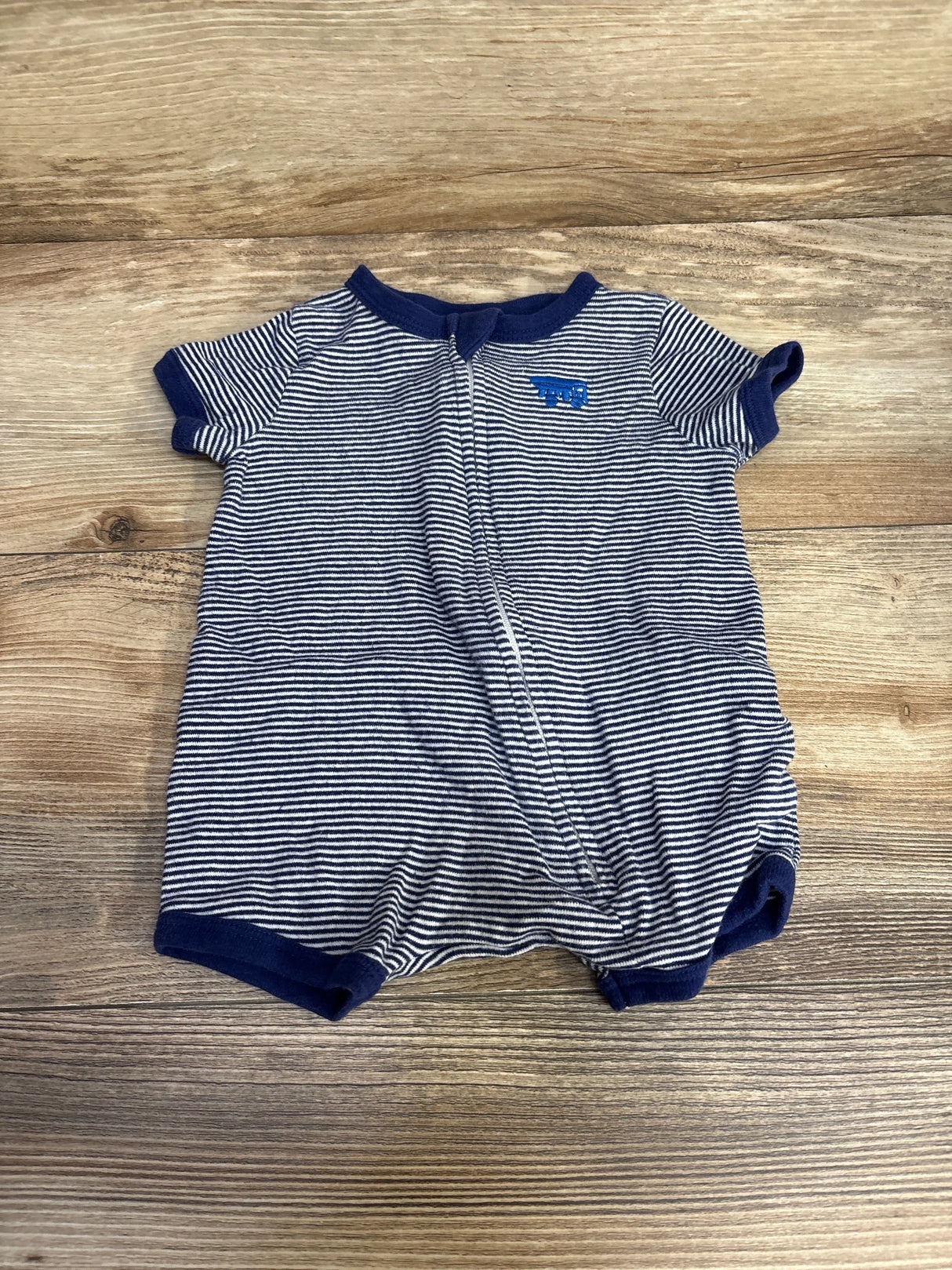 Flat lay of navy and white striped shortie romper showing front zipper closure and embroidered blue elephant on wood background