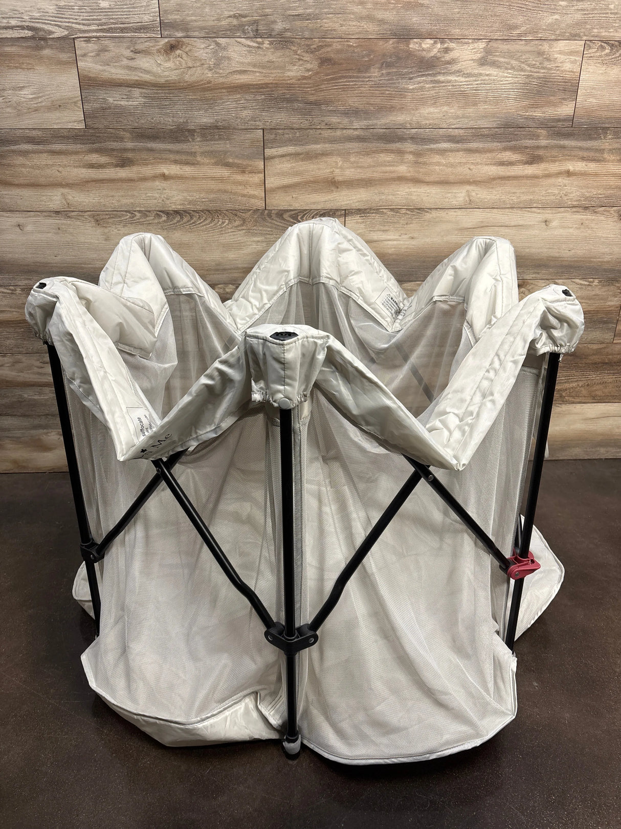 Collapsible mesh pet playpen with black frame on wood floor background