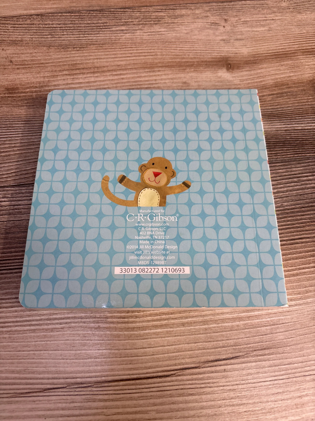 C.R. Gibson baby memory book with monkey design on blue patterned cover, wooden background