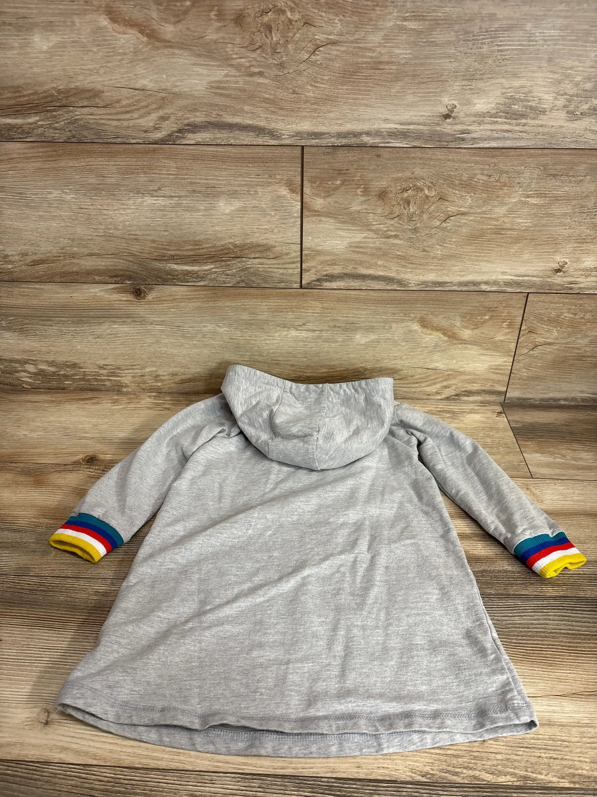 Flat-lay back view of girls' grey hooded sweater dress 4T showing rainbow-striped cuffs on wood background
