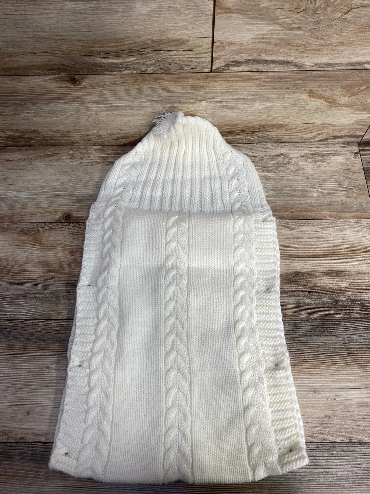 White cable knit hat and scarf set on wooden background