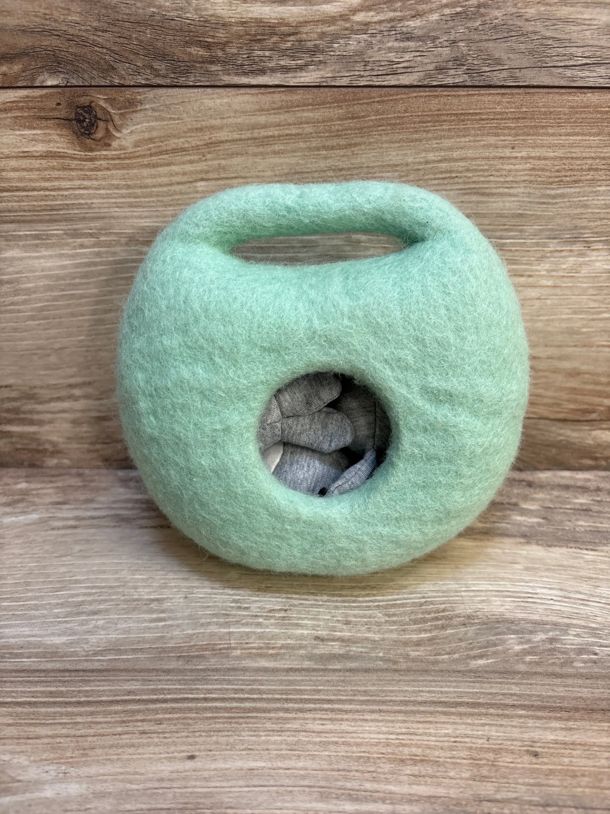 Soft mint green felted wool toy with handle and circular window, stuffed with plush animals
