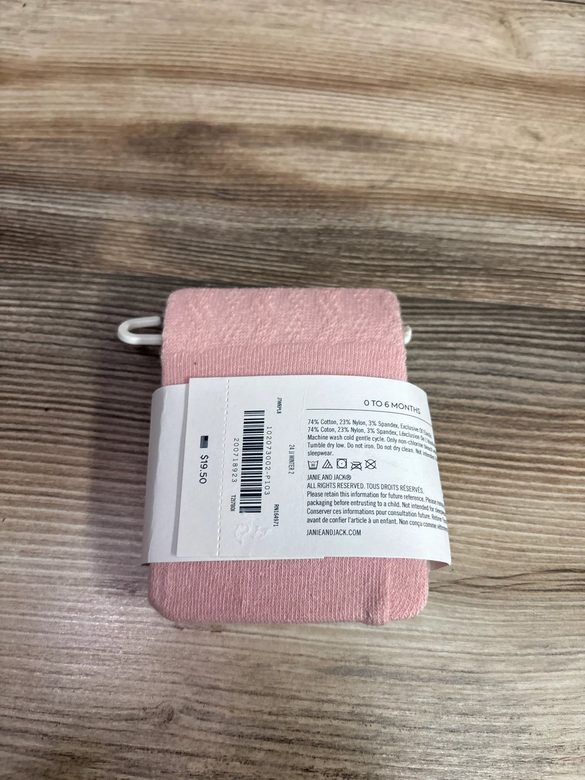 Top view of pink Janie and Jack tights showcasing ribbed knit texture with a 0 to 6 months label on a wood surface