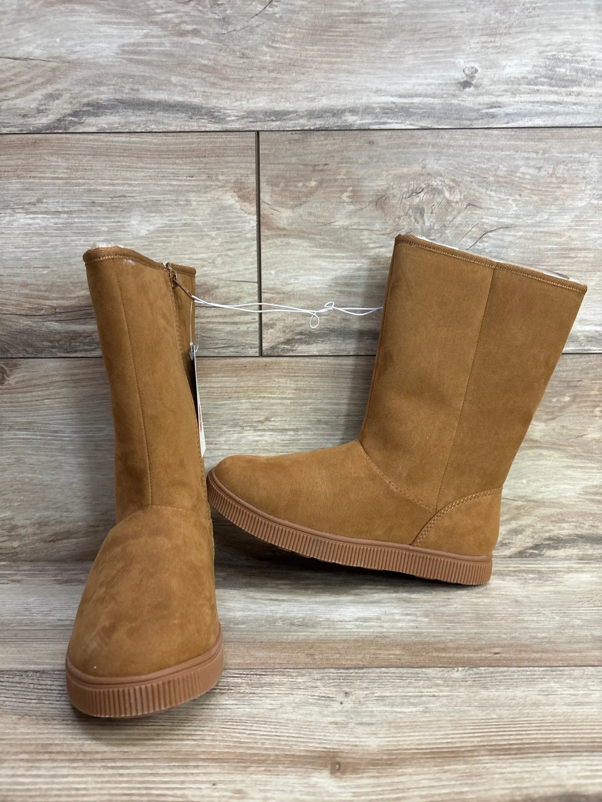 Kids brown suede winter boots with flat rubber soles on wood floor