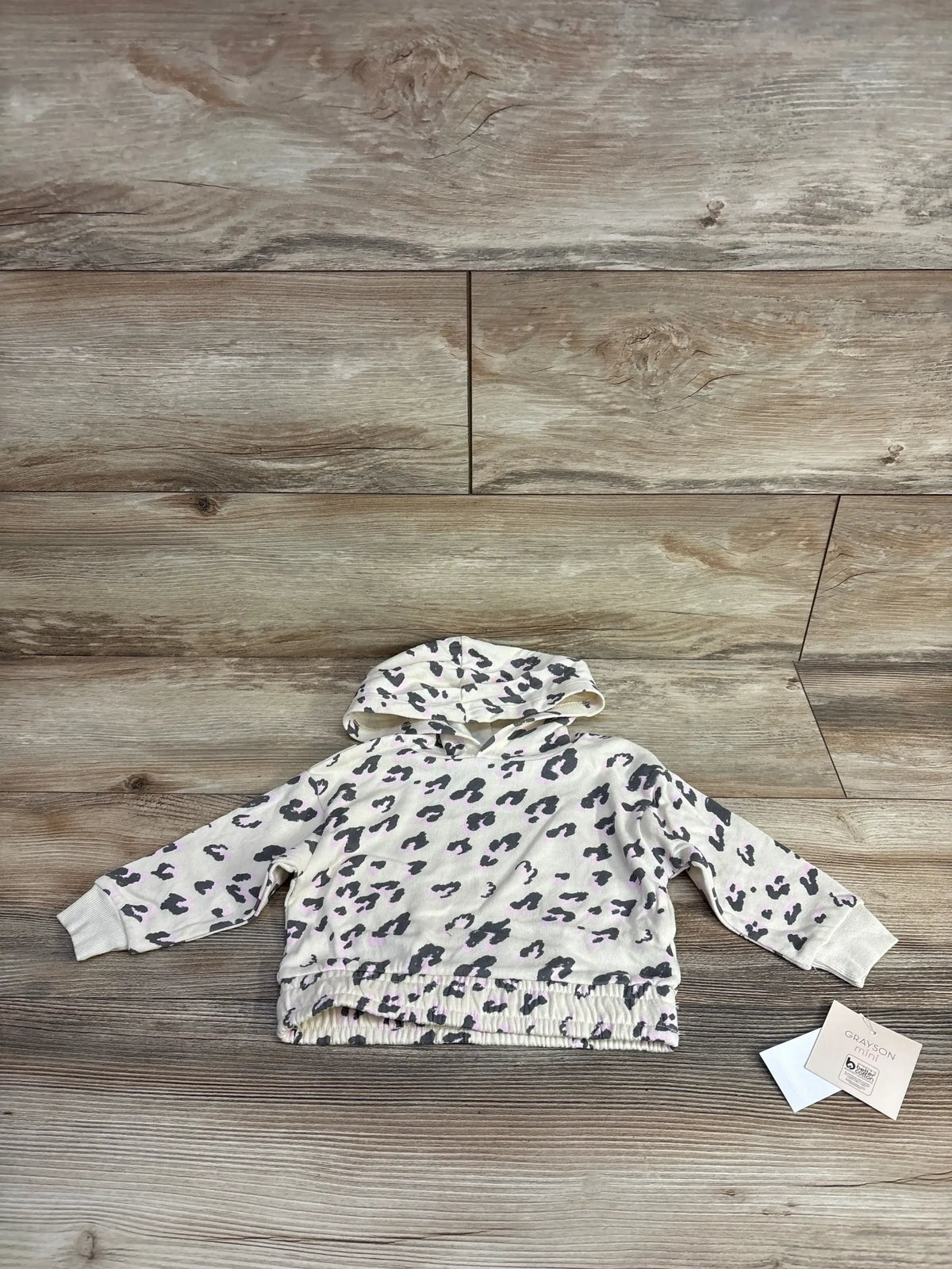 Infant leopard print hooded sweatshirt on wood floor, cozy baby clothing