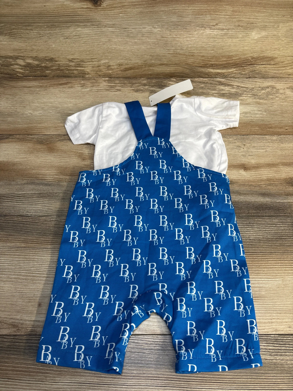 Blue baby overalls with 'BABY' print and white shirt, kids clothing set on wood floor