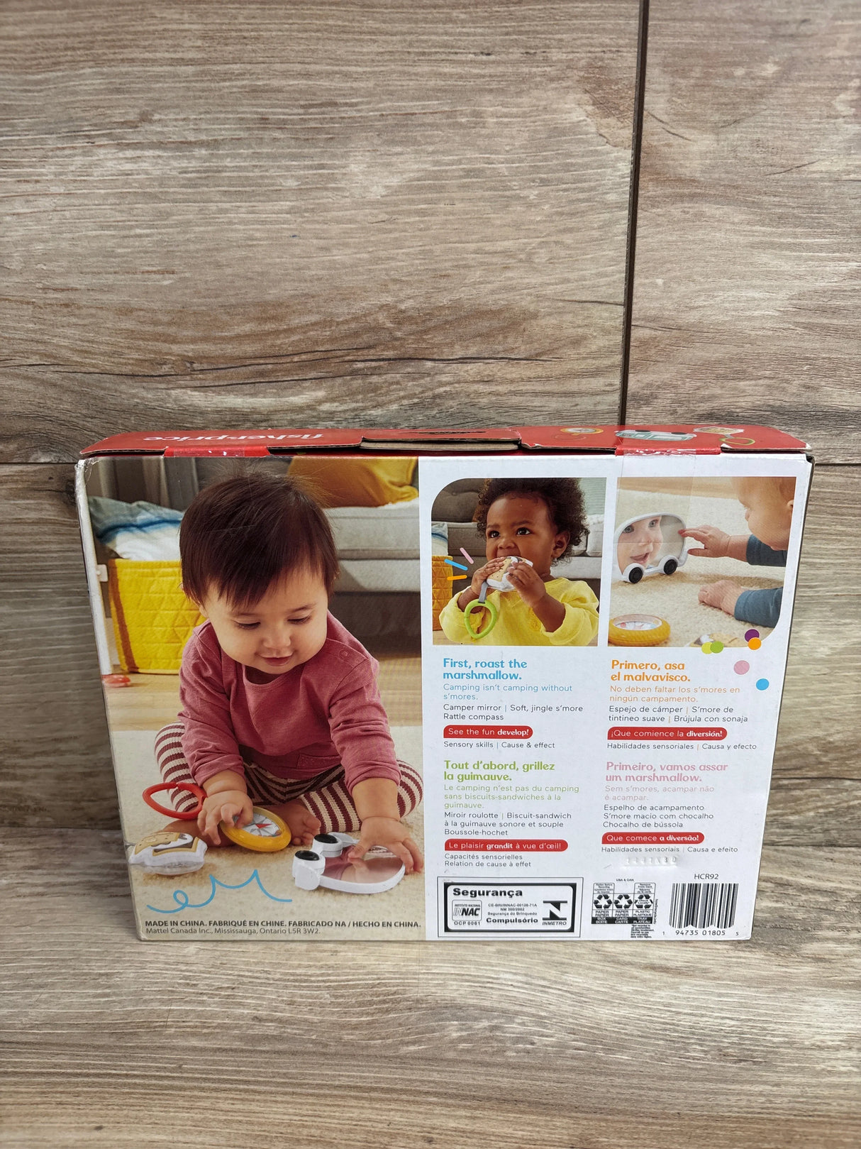 Back of Fisher-Price S’more Fun Camping Gift Set showing s’more, compass, and camper mirror toys on wood flooring