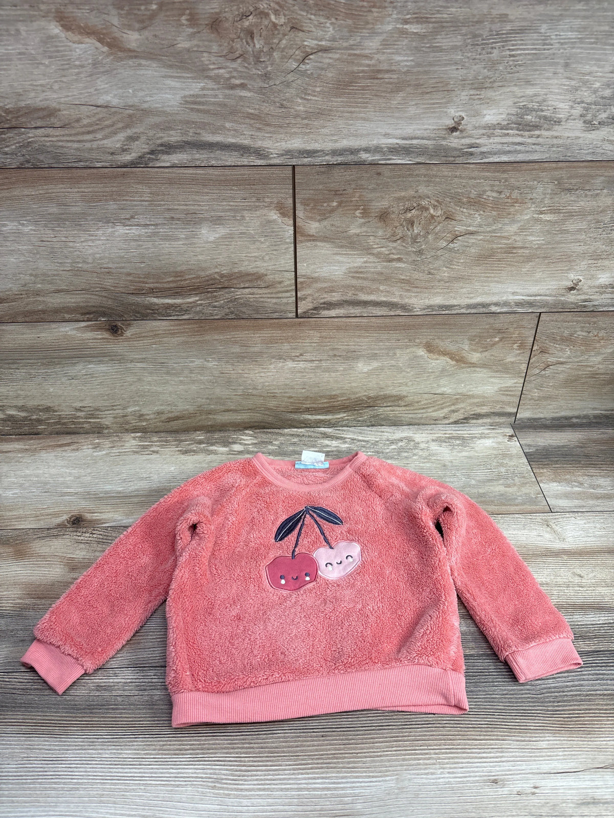 Pekkle plush red cherry sweatshirt for toddlers, size 24m, on a wood background