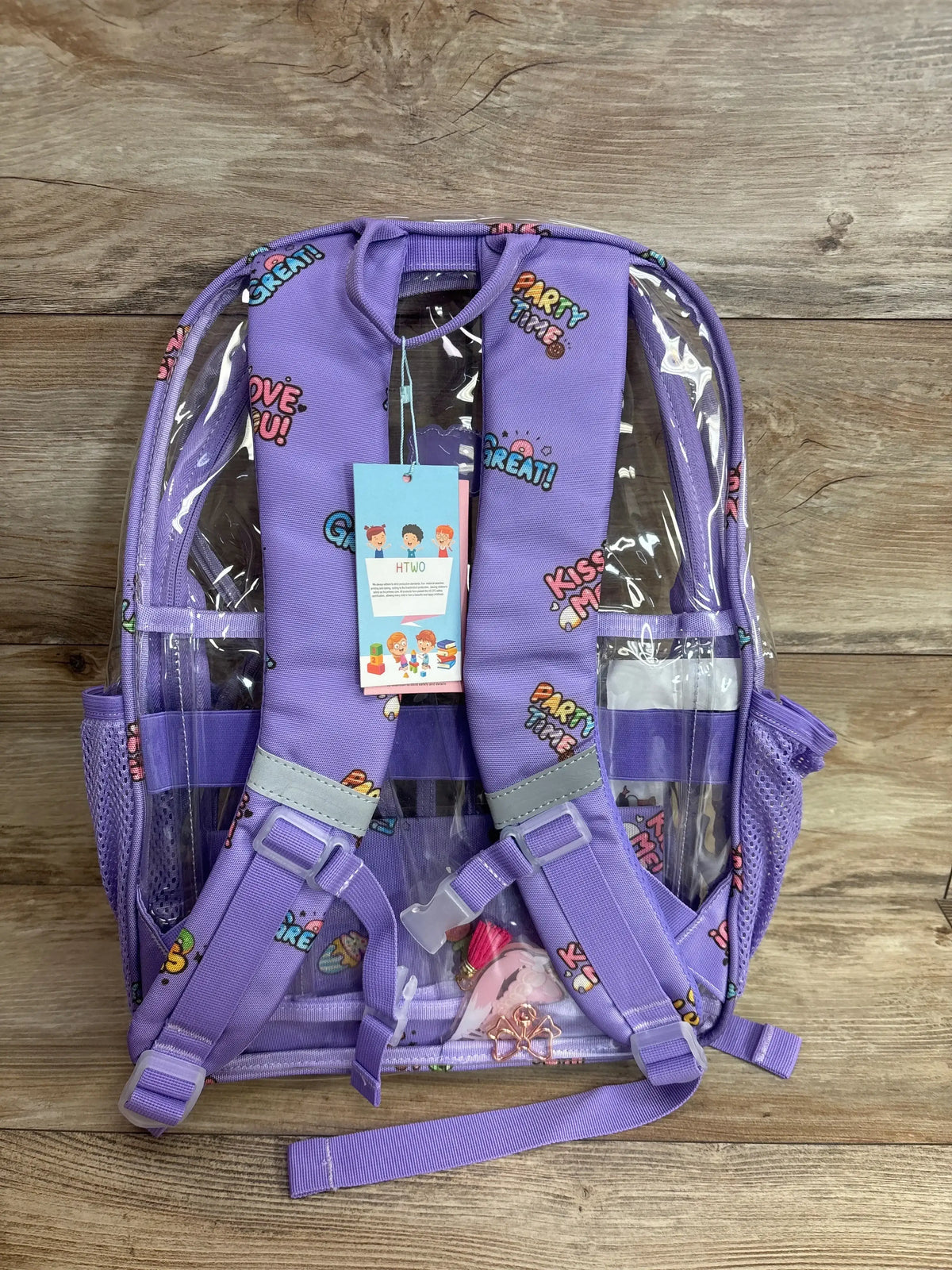 Rear view of purple clear HTWO backpack showcasing patterned straps, transparent pockets, and side mesh bottle pockets on a wood floor